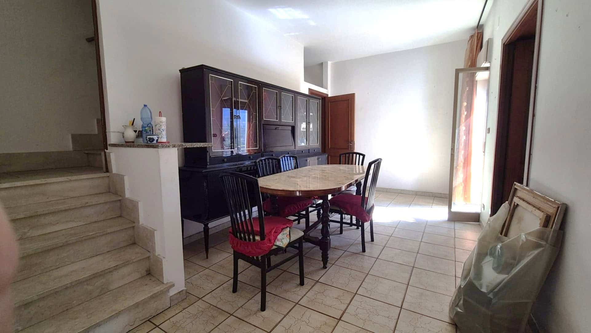 Ampia sala da pranzo con tavolo rotondo e sedie in legno, arredi classici e pareti luminose, ideale per convivialità e momenti di relax in casa.