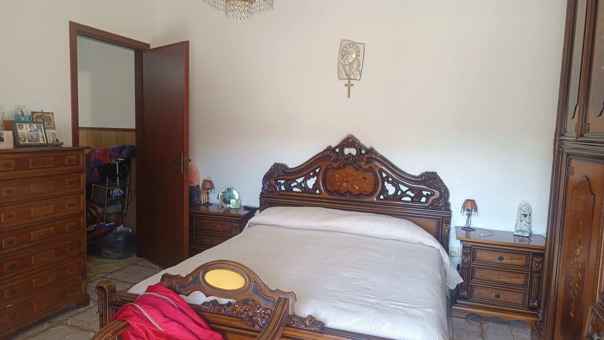 Letto matrimoniale in stile classico con testiera intagliata in legno, in una camera da letto tradizionale.
