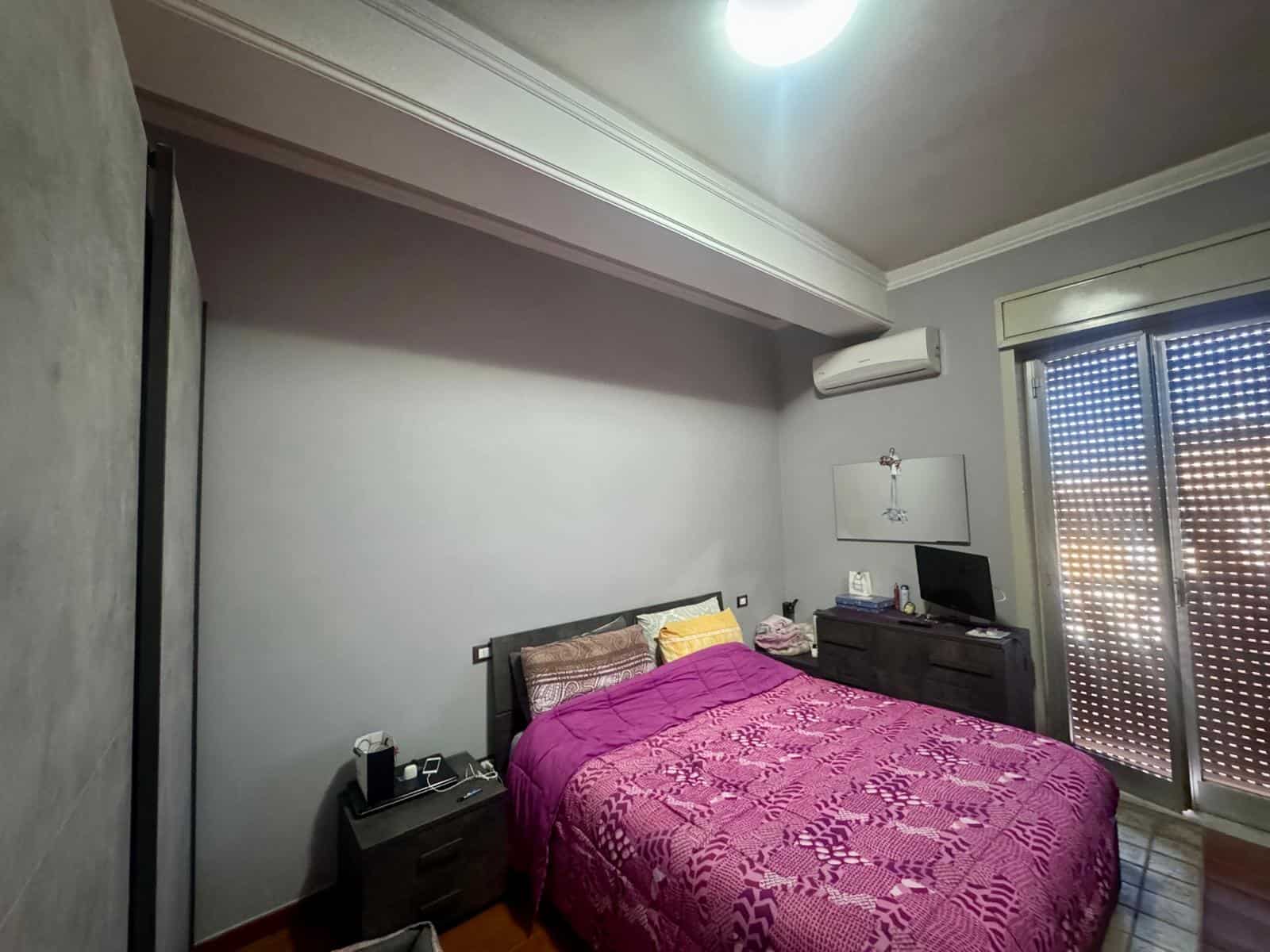 Letto matrimoniale con biancheria colorata, in una camera moderna con aria condizionata e accessori tecnologici, ideale per soggiorni confortevoli e rilassanti.