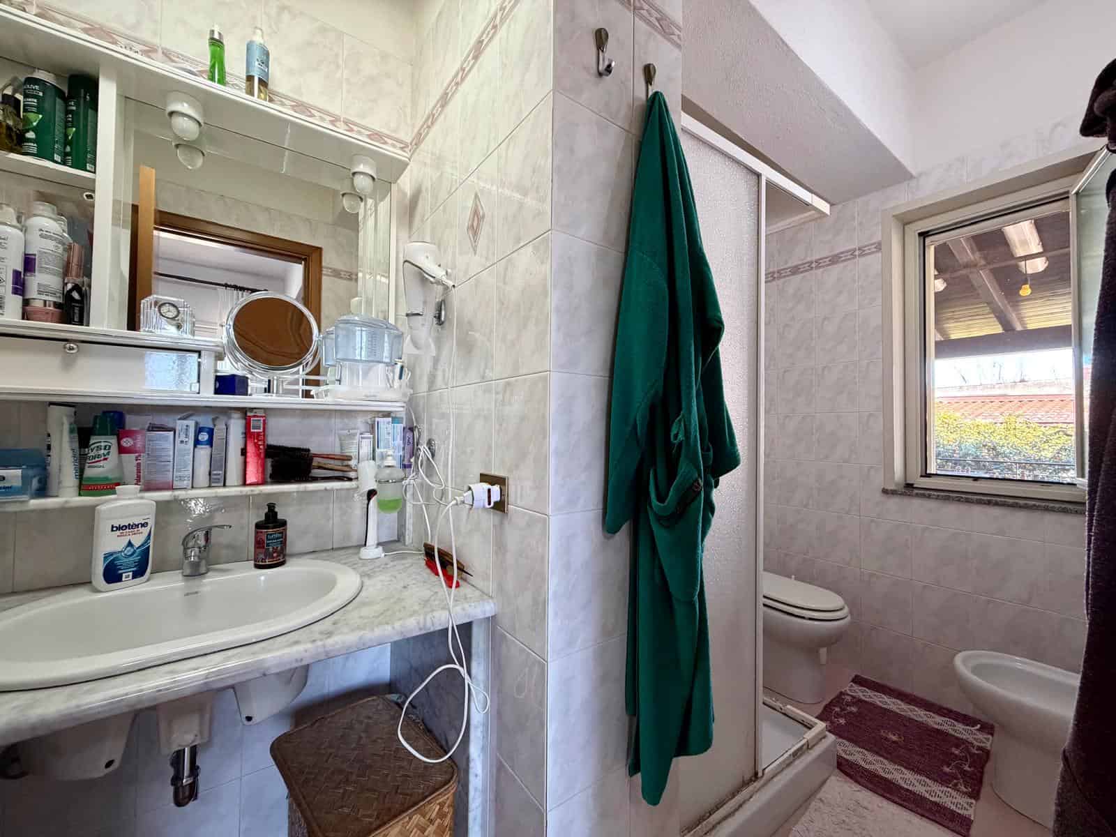 Specchio e lavabo in bagno con accessori e prodotti per l'igiene personale, ambiente luminoso e funzionale.