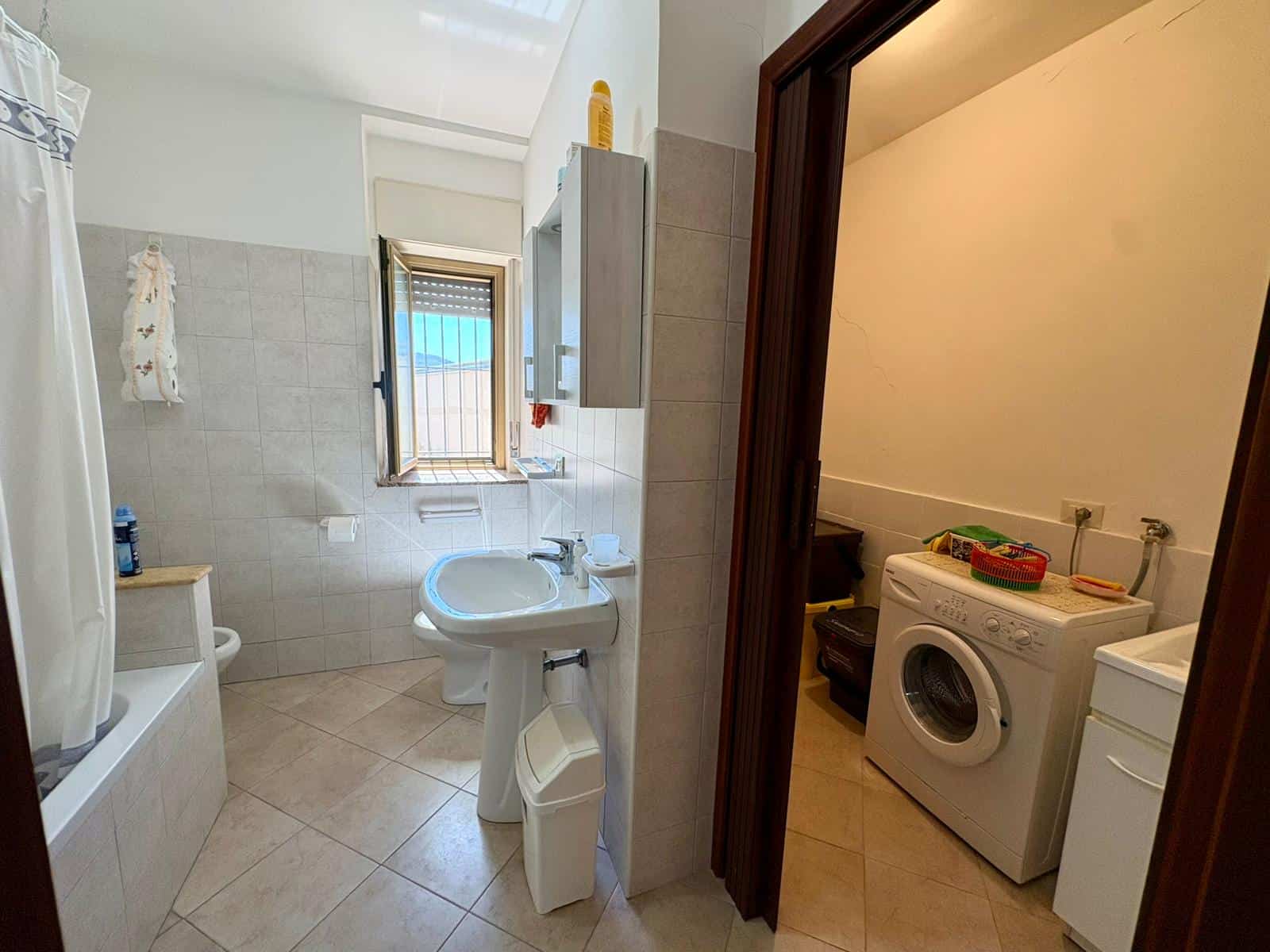 Lavabo e finestra in bagno con accesso alla lavanderia, ambiente luminoso e funzionale, ideale per la gestione quotidiana delle faccende domestiche e il comfort abitativo.