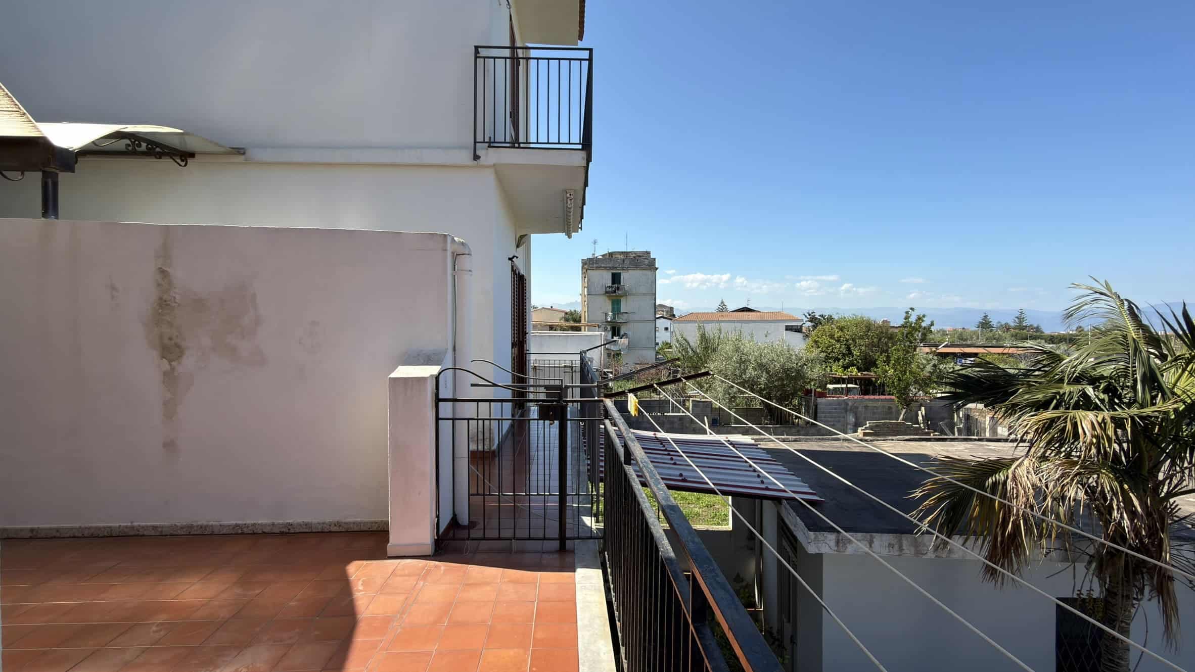 Balcone con pannelli solari e vista panoramica sulla città e il mare, in un ambiente residenziale soleggiato e tranquillo. Ideale per relax e attività all'aperto, con spazio per piante e mobili da est.