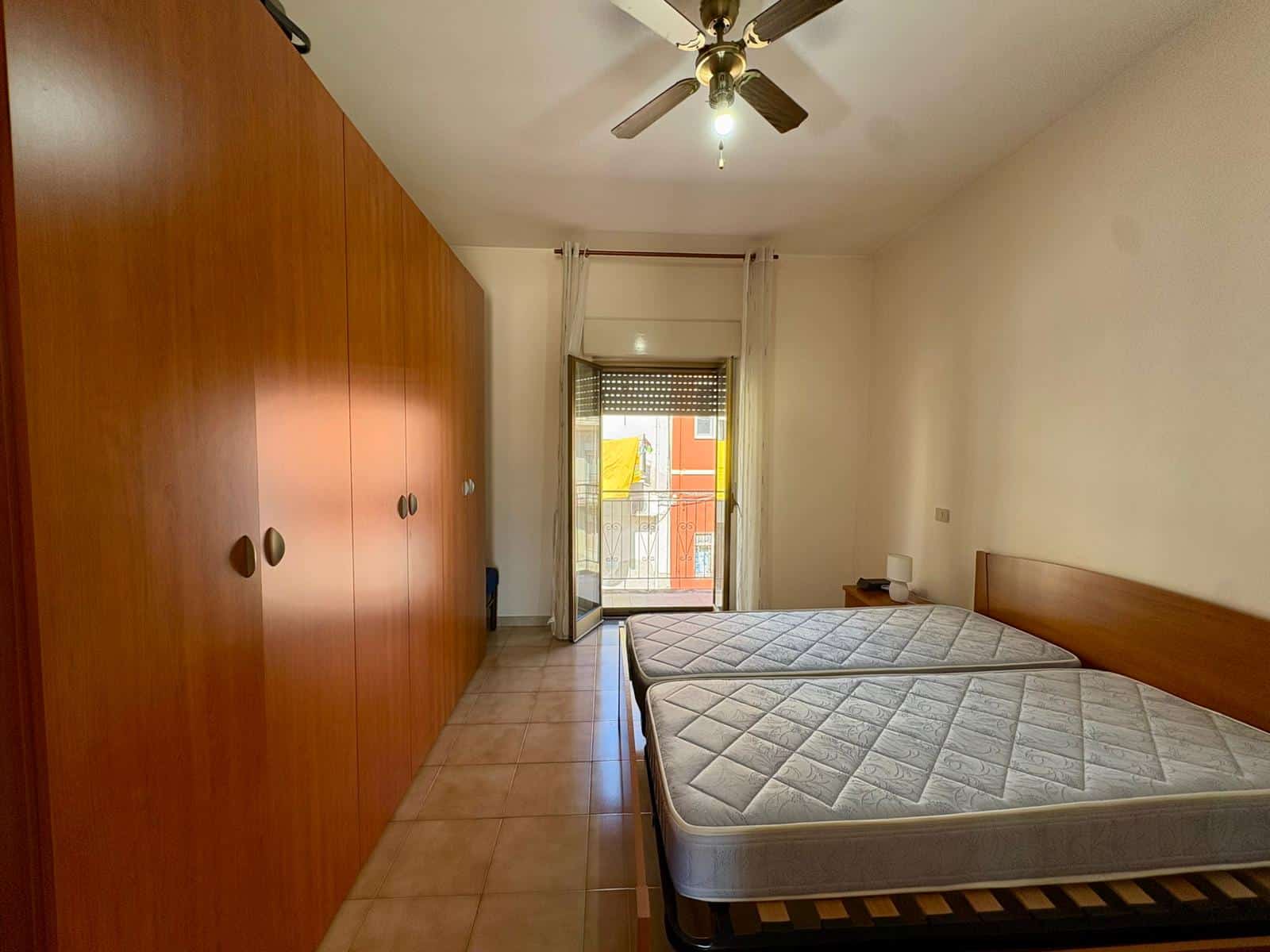 Letto matrimoniale con armadio a muro in una camera da letto luminosa e spaziosa, con porta finestra che dà su un balcone. Ambientazione moderna e funzionale, ideale per residenze di qualità.