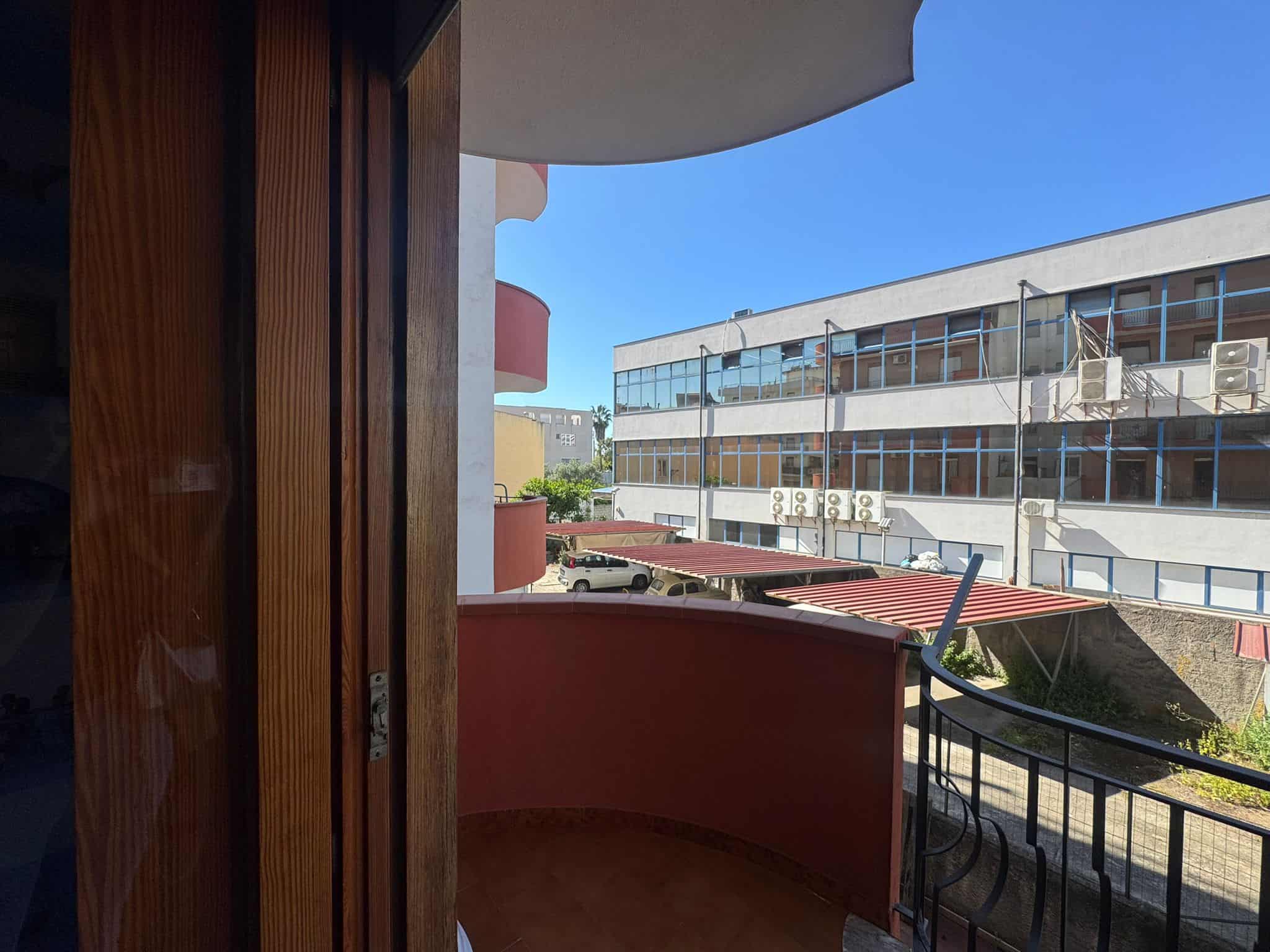 Balcone di un appartamento moderno con vista sulla città, con ringhiera in metallo e pareti colorate, in un complesso residenziale contemporaneo.