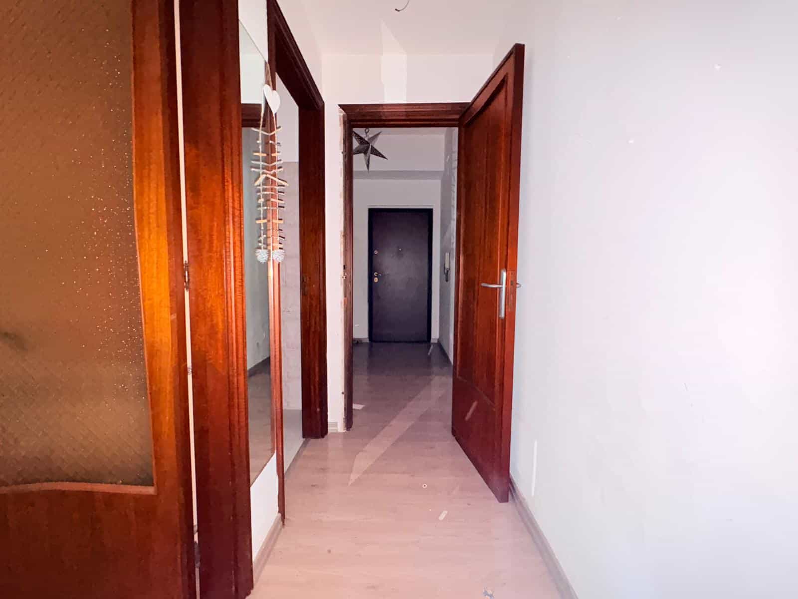 Ampia entrata di casa con porte in legno e pavimento in marmo, ambiente luminoso e accogliente, ideale per vivere in comfort e stile.