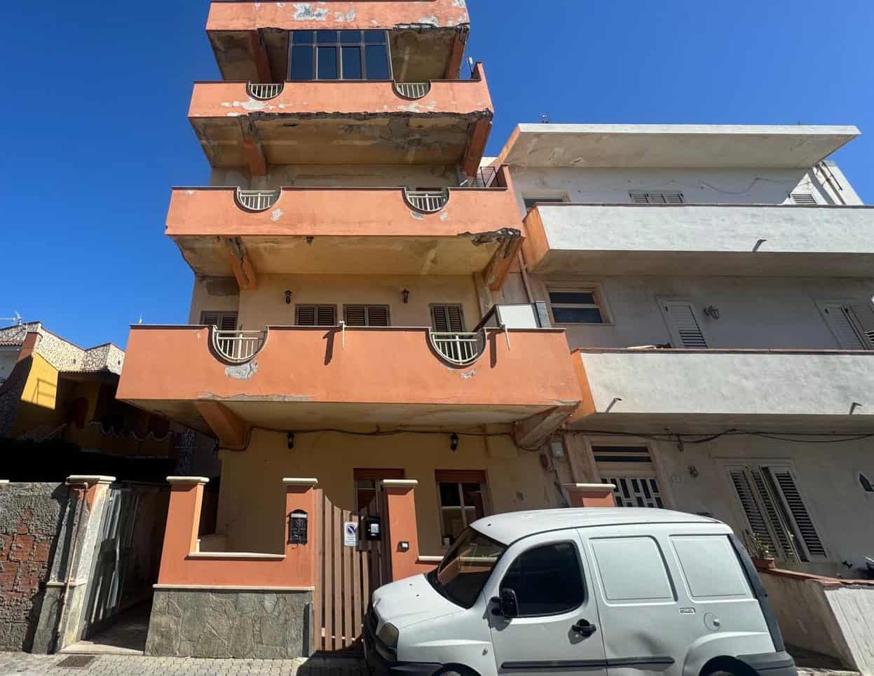 Vano residenziale in costruzione con balconi e facciata colorata, situato in un quartiere urbano. Edificio multifamiliare con parcheggio e accesso pedonale, pronto per personalizzazione e finiture int.