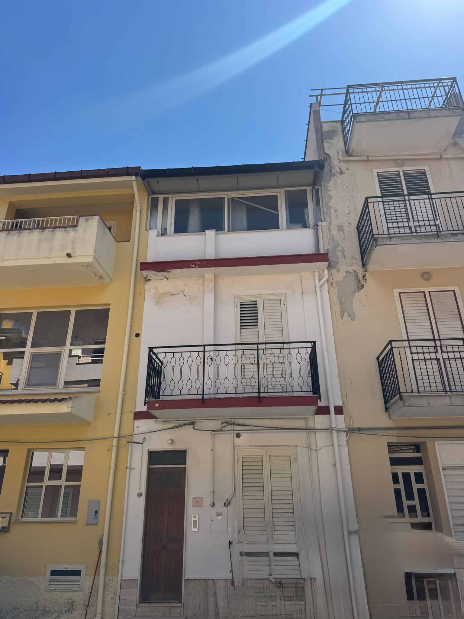 Balcone di un edificio residenziale in centro città con vista sul cielo azzurro, facciata bianca e dettagli in ferro battuto, in stile urbano e moderno, perfetto per investimenti immobiliari o abitazi.