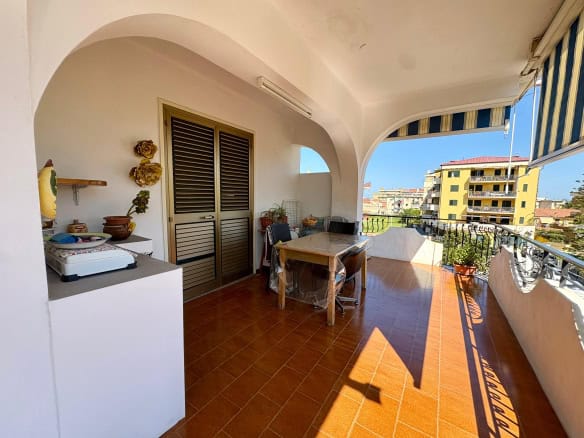 Balcone spazioso con vista sul quartiere residenziale, arredato con tavolo e sedie, ideale per relax e cene all'aperto, in un appartamento luminoso e ben ventilato in Italia.