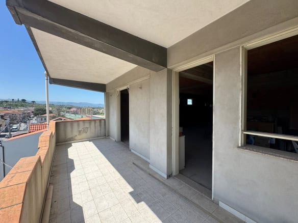 Balcone di un appartamento in fase di costruzione con vista panoramica sulla città e sul paesaggio circostante, con pareti in cemento e pavimento in piastrelle chiare.