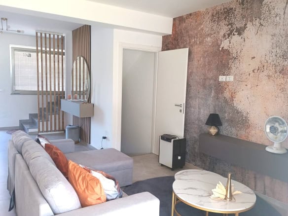 Interno moderno di un appartamento con divano, parete decorativa e accessori di design, ideale per soggiorni confortevoli e di stile.