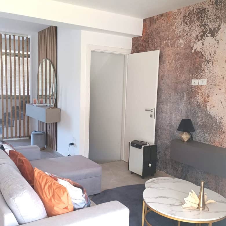 Interno moderno di un appartamento con divano, parete decorativa e accessori di design, ideale per soggiorni confortevoli e di stile.