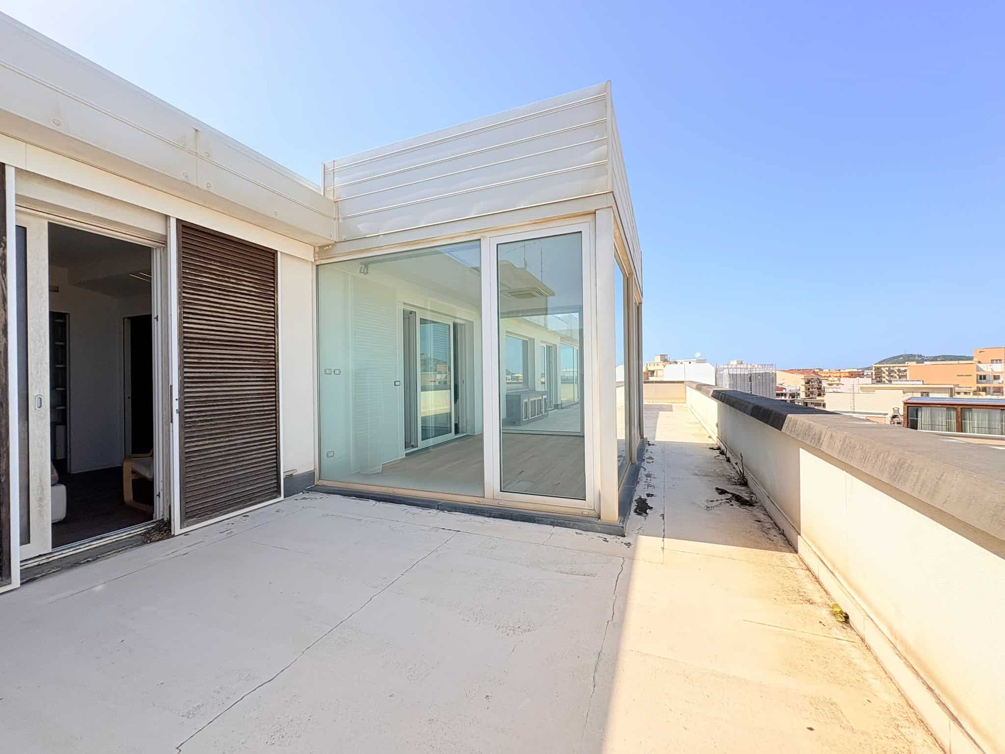 Immagine di un terrazzo di un appartamento moderno con vista sulla città, con pareti in vetro e spazio aperto, ideale per relax e intrattenimento.