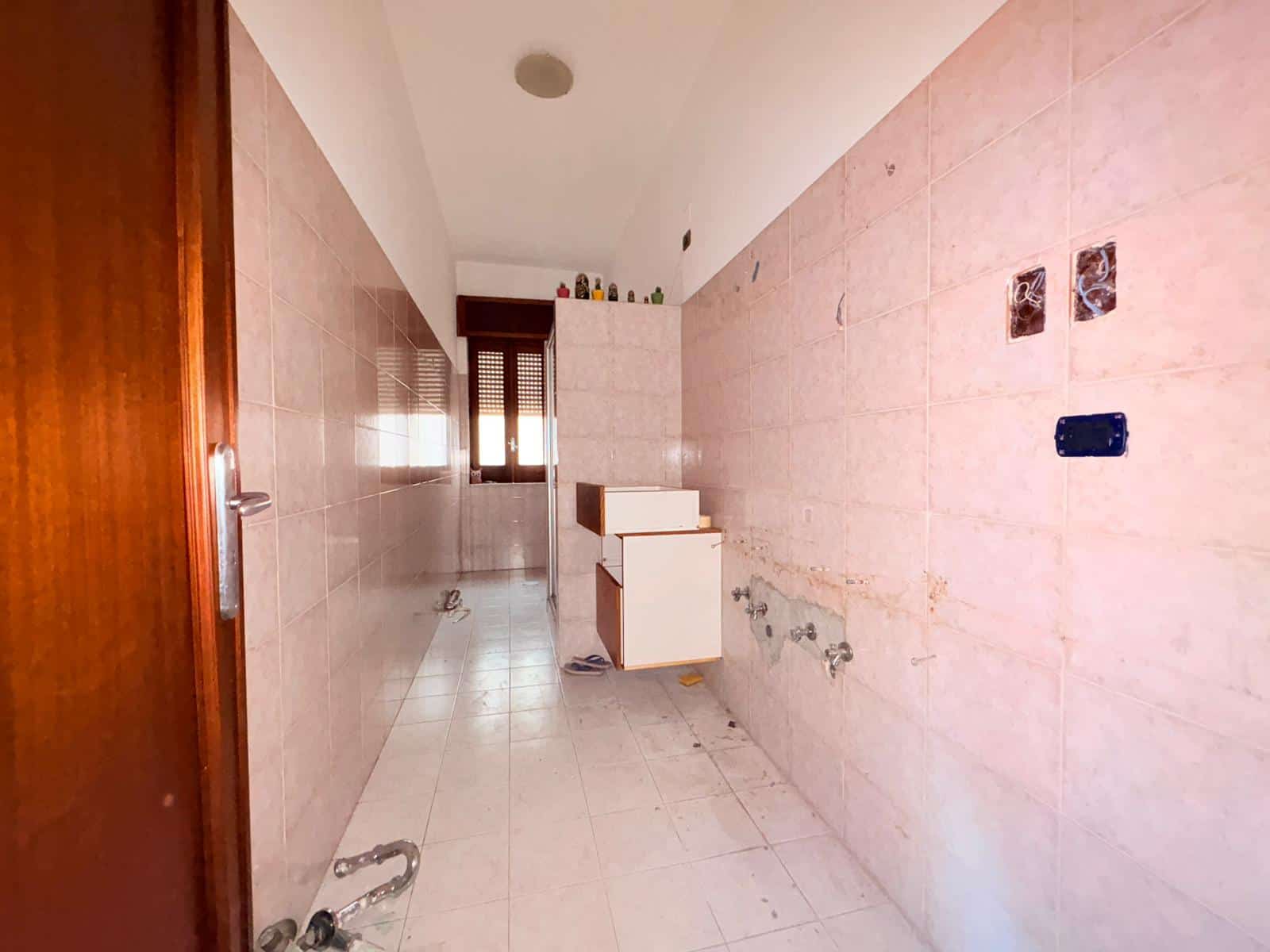 Lavandino e pareti in piastrelle rosa in un bagno in fase di ristrutturazione, con spazio per installare sanitari e accessori. Ideale per ristrutturare un bagno moderno e funzionale.