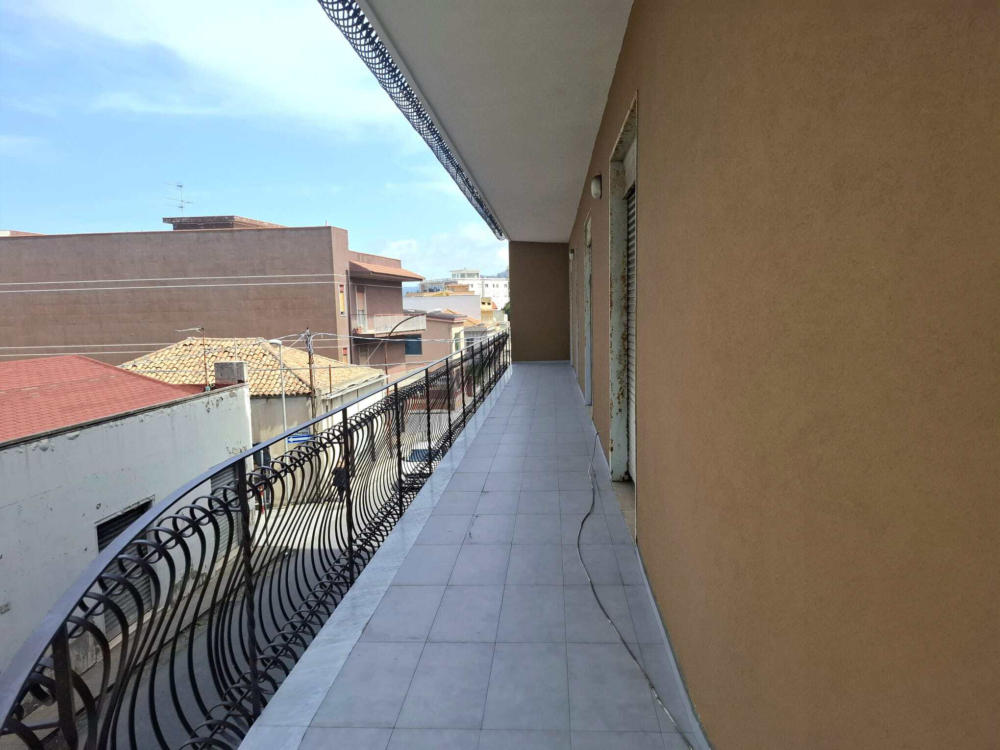 Balcone spazioso con vista urbana, pavimentato in piastrelle e ringhiera decorativa in ferro, ideale per relax e momenti all'aperto in un appartamento in città.