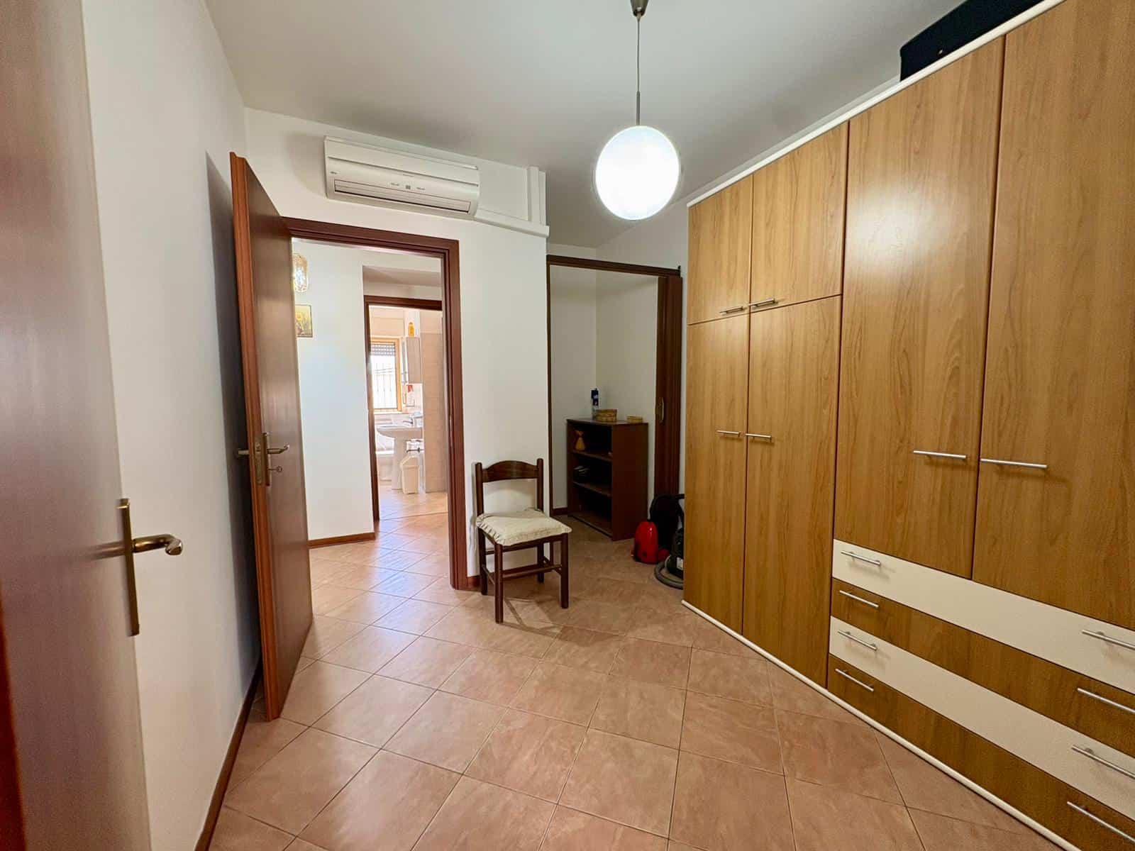 Ampio armadio a muro in legno con cassetti e ante, ideale per organizzare l'abbigliamento in camera da letto. Spazio funzionale e moderno, perfetto per ottimizzare gli ambienti domestici.
