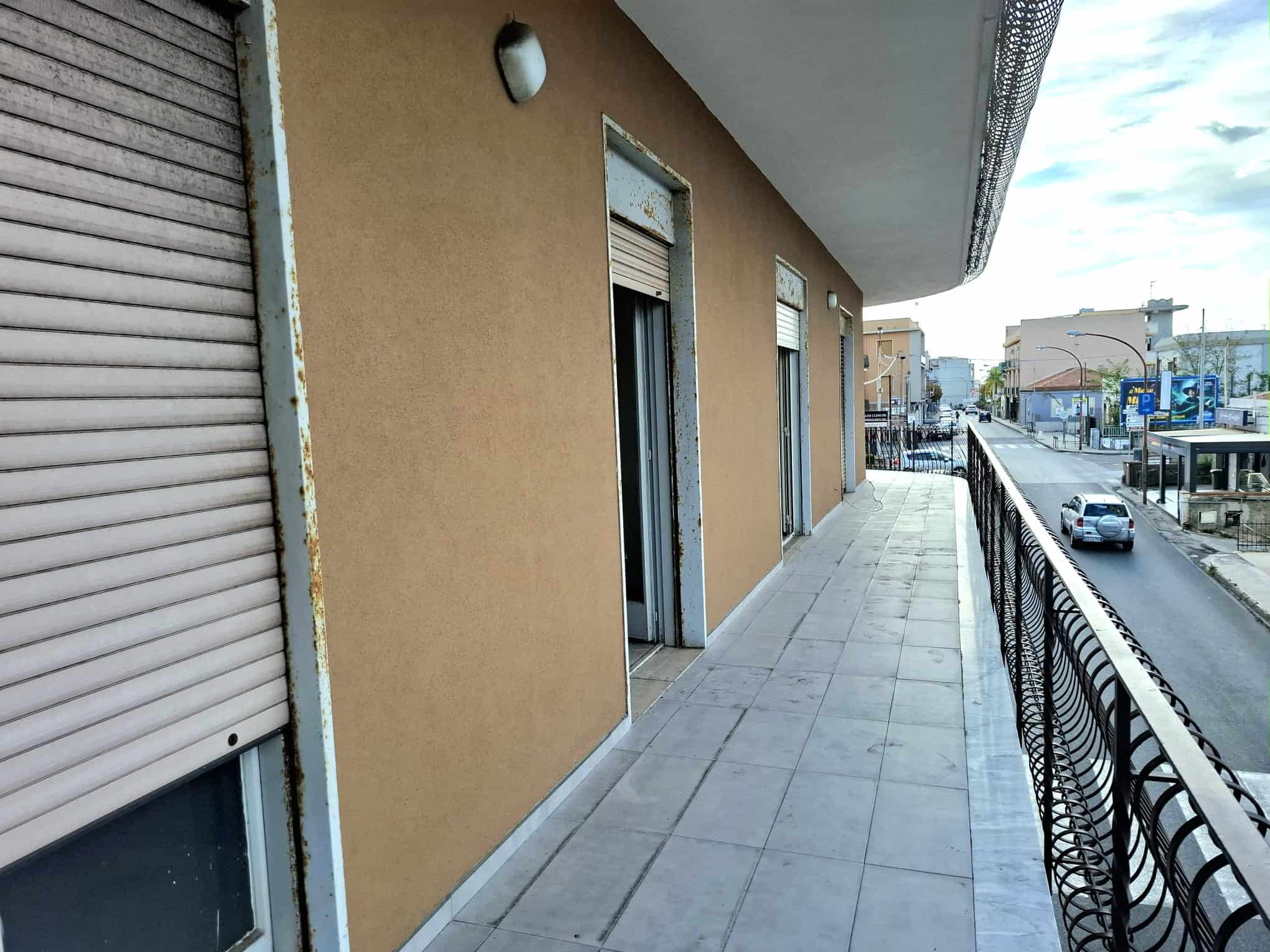 Ampia terrazza con vista sulla strada, con pavimentazione in piastrelle e ringhiera in ferro battuto, ideale per relax e momenti all'aperto in zona urbana.