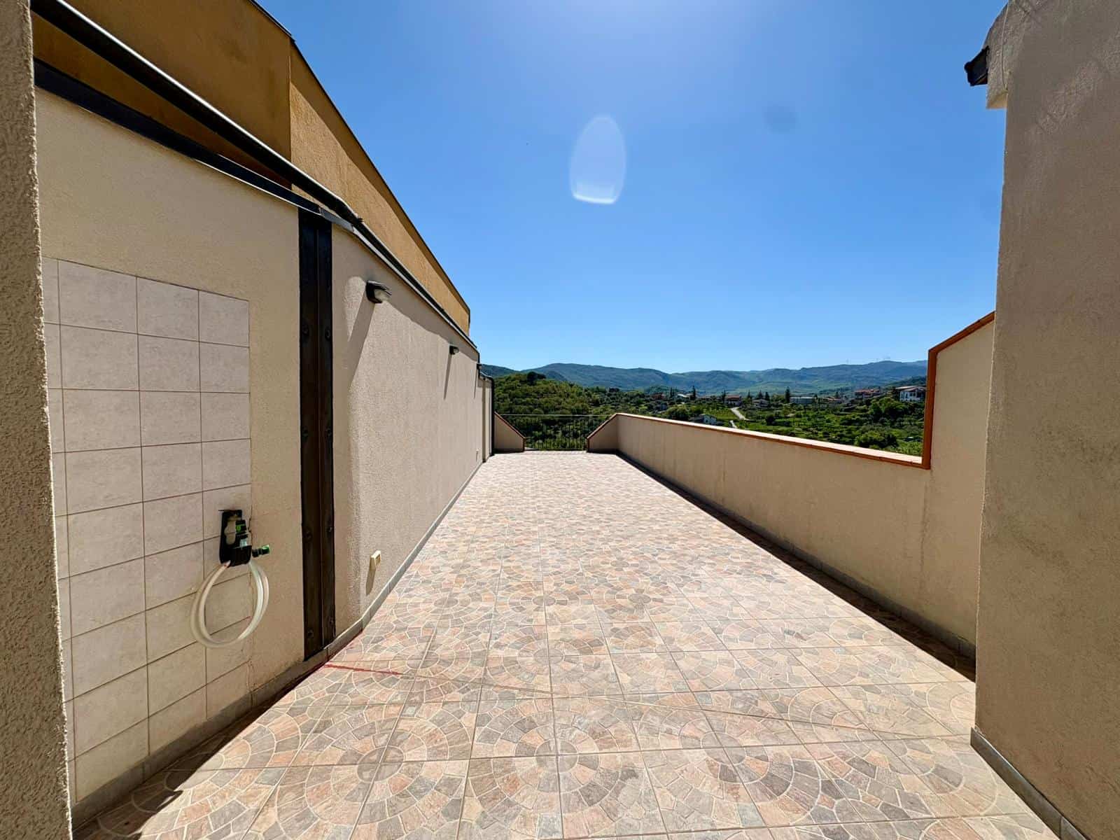Ampia terrazza panoramica con vista sulle colline toscane, ideale per relax e momenti all'aperto, con pavimentazione in gres porcellanato resistente e parapetto in muratura.