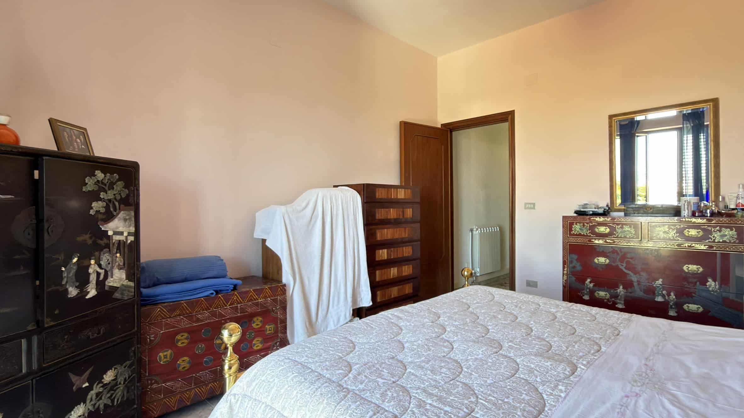 Ampia camera da letto con arredi classici, letto matrimoniale e armadio, ambiente luminoso e accogliente, ideale per soggiorni confortevoli in immobili di pregio a NextCasa.