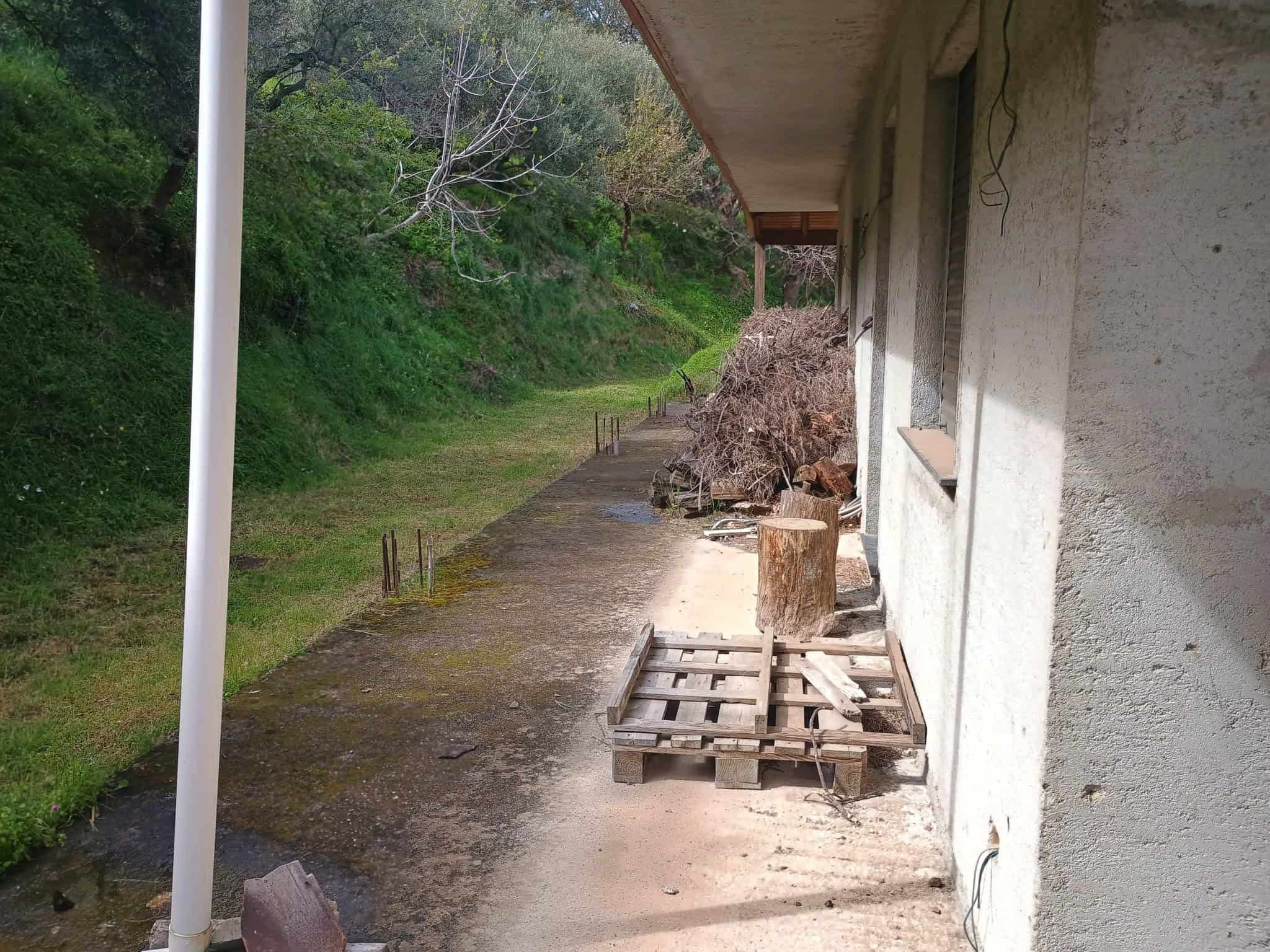 Pannello solare installato sul tetto di una casa in campagna, con vista su un sentiero naturale e vegetazione circostante, in un ambiente rurale e tranquillo.