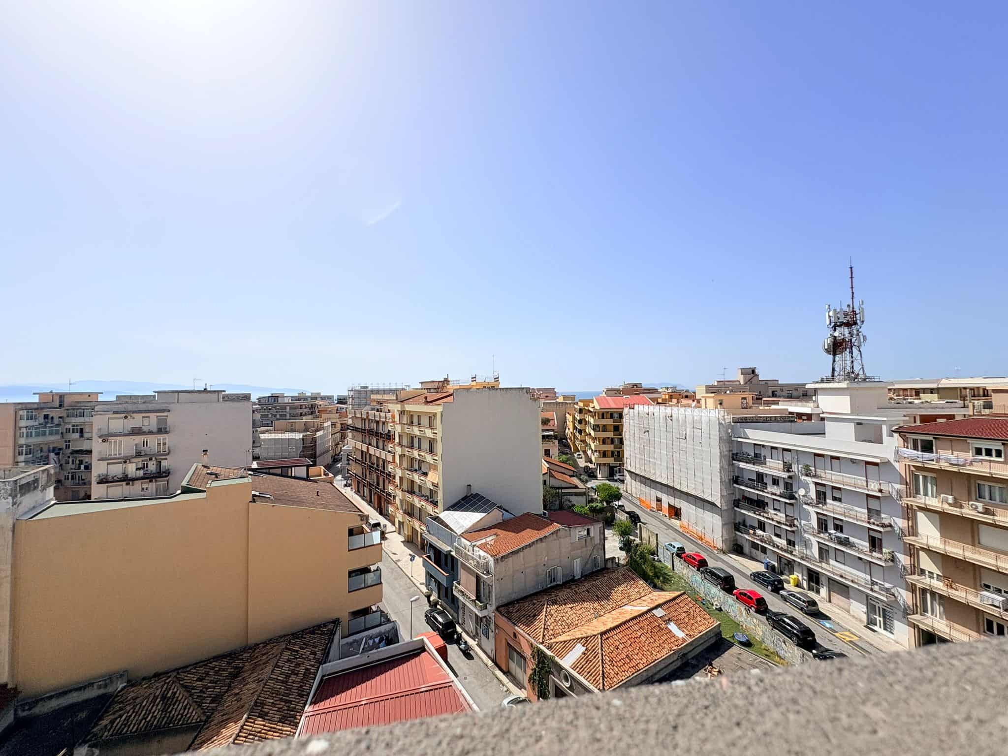 Balcone con vista sulla città di Napoli, con edifici residenziali e strade trafficate sotto un cielo sereno e soleggiato.