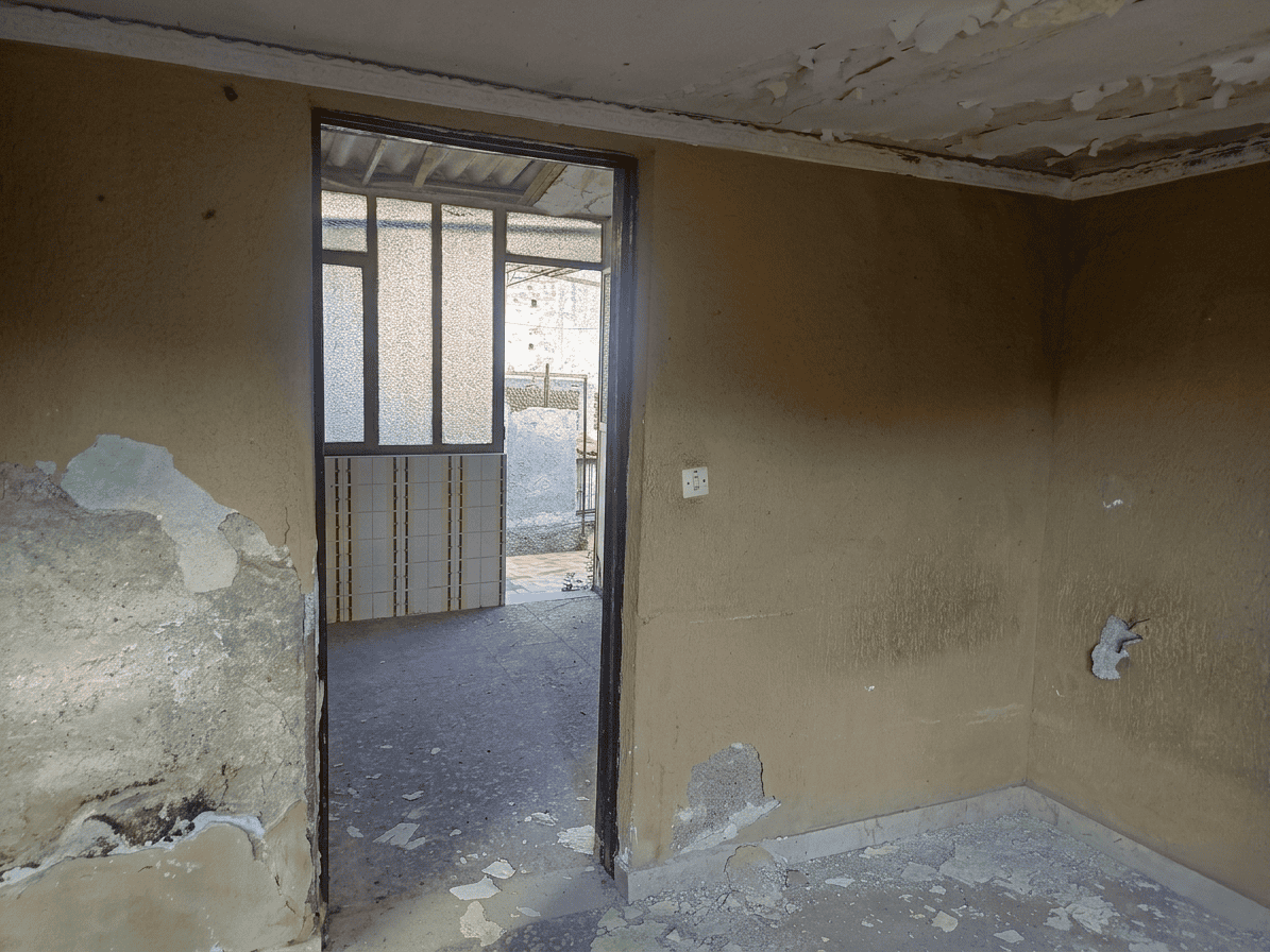 Vano interno di una casa in ristrutturazione con pareti danneggiate e soffitto in cattive condizioni, pronto per lavori di ristrutturazione e riqualificazione edilizia.