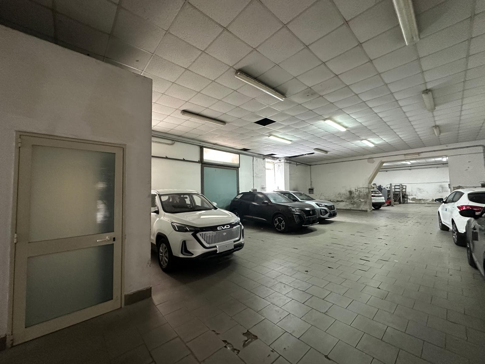 Auto in un garage coperto, parcheggio interno con diverse vetture moderne e spazio disponibile.