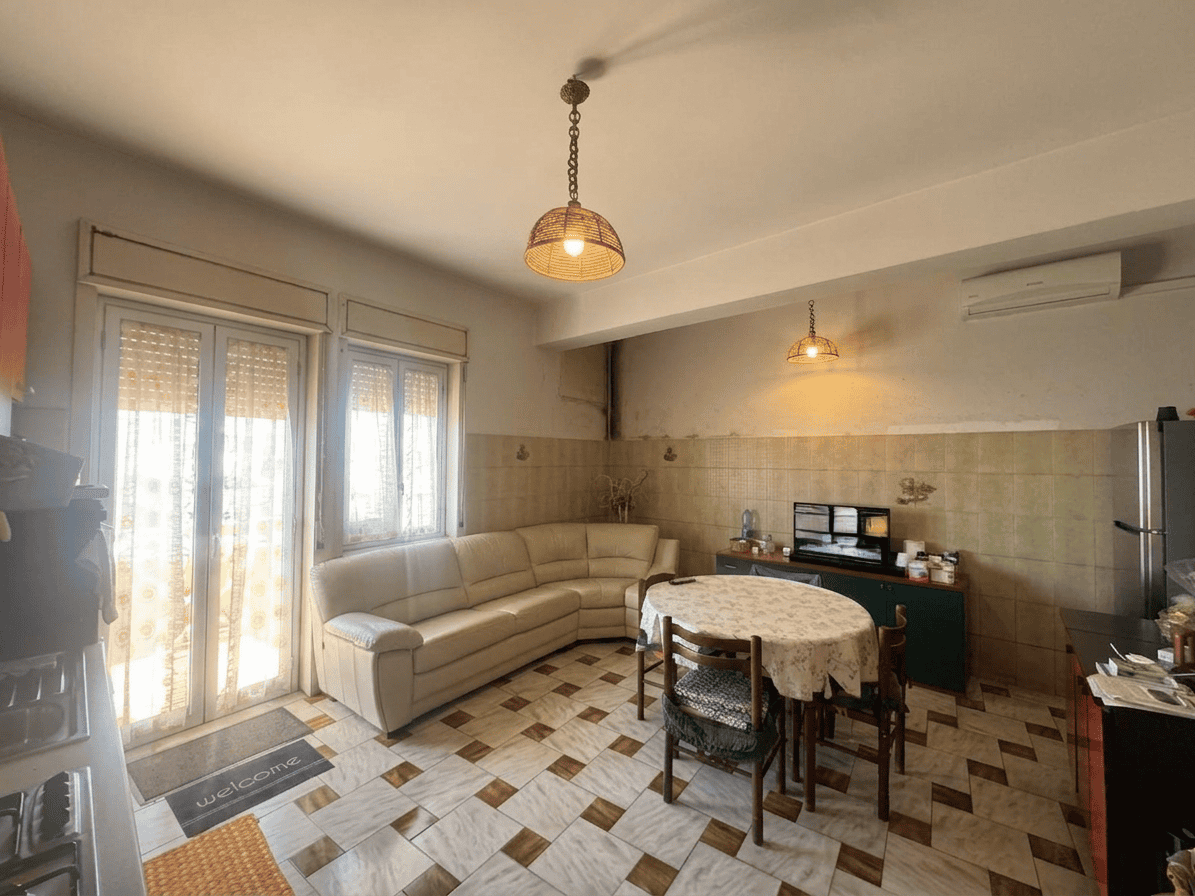 Aria luminosa e accogliente con soggiorno e zona pranzo, illuminata da lampade vintage, con accesso a balcone e arredamento funzionale.