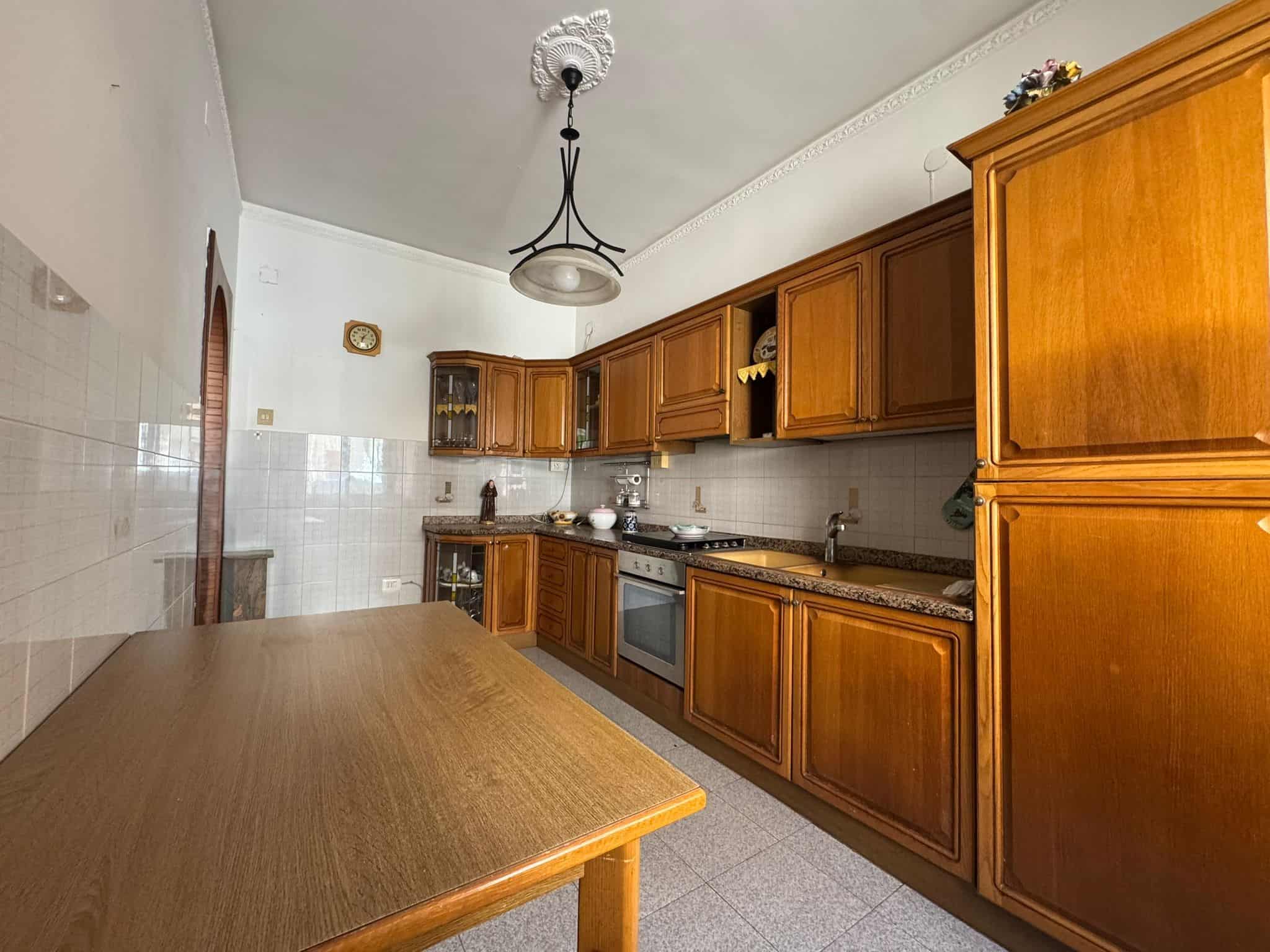 Ampia cucina con mobili in legno, piano di lavoro in granito e elettrodomestici moderni, ambiente luminoso e accogliente, ideale per preparare pasti in famiglia o con amici.
