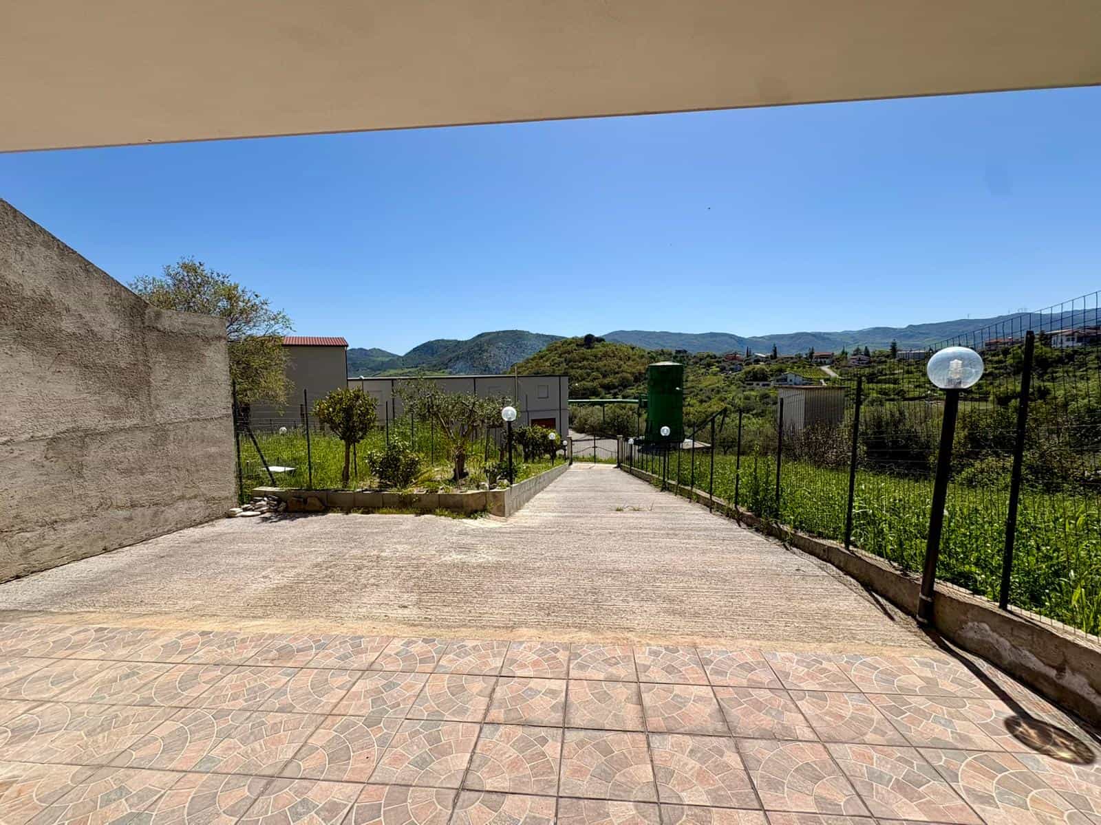 Panchina in giardino con vista panoramica sulle colline e cielo sereno, spazio esterno ben curato e tranquillo, ideale per relax e momenti di convivialità all'aperto.