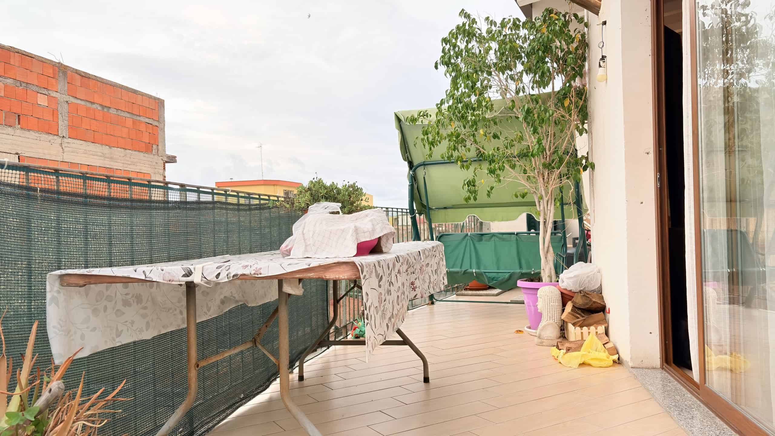 Balcone con vista su giardino e arredi esterni, ambiente luminoso e accogliente, ideale per relax e convivialità all'aperto.