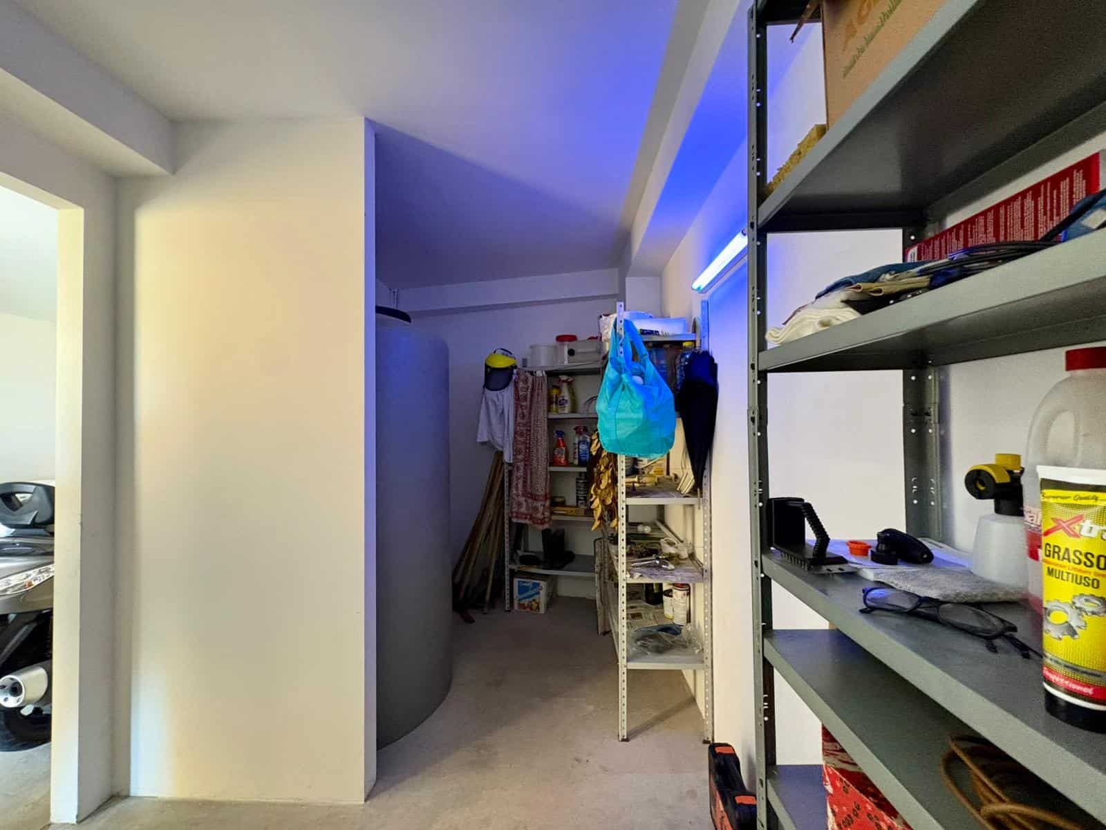 Soggiorno moderno con scaffali e oggetti di bricolage, illuminazione a LED blu, spazio funzionale e ben organizzato per attività domestiche e hobby.