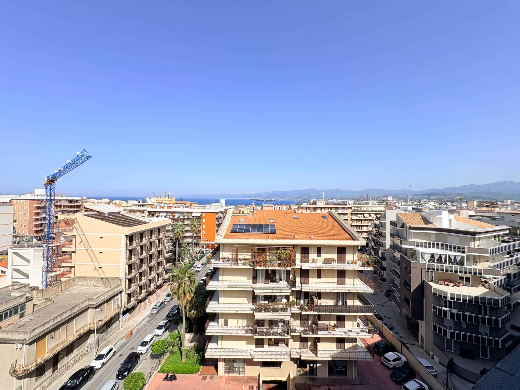 Vasto panorama urbano con edifici moderni e un cielo sereno, vista dalla terrazza di un appartamento in centro città, con dettagli di costruzioni e un paesaggio urbano in lontananza.