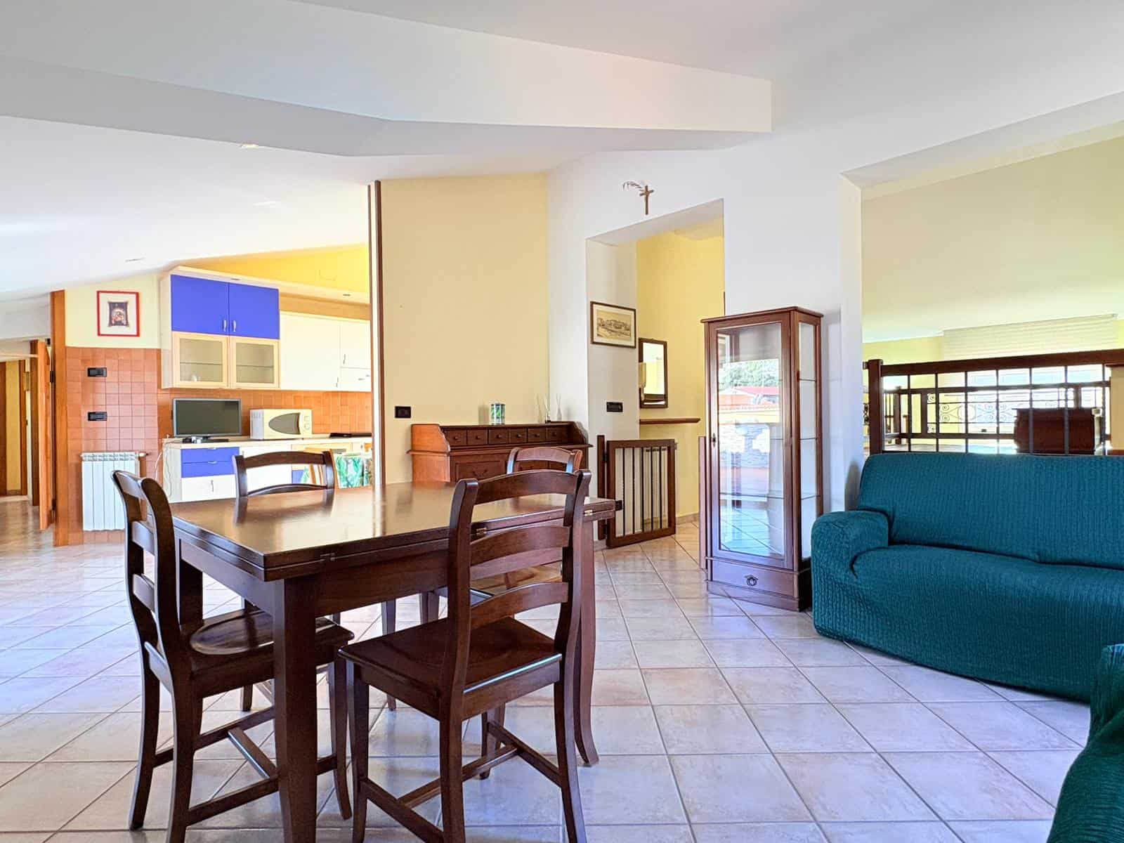 Appartamento spazioso con zona pranzo e soggiorno luminoso, arredato con mobili in legno e divano blu, ideale per famiglie o gruppi di amici in cerca di comfort e stile.