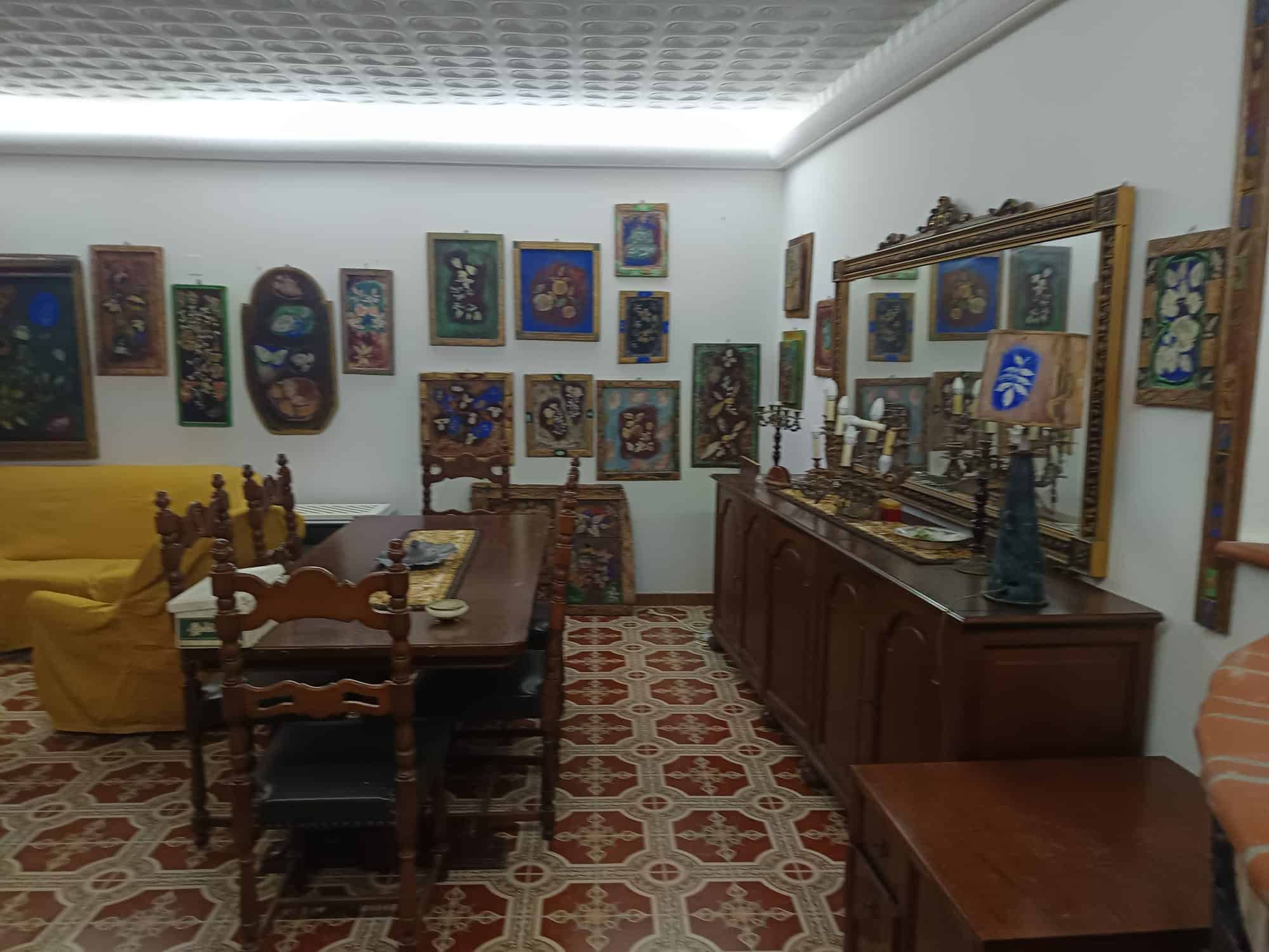 Pannello di opere d'arte e dipinti colorati in una galleria o studio artistico con mobili in legno e decorazioni artistiche.