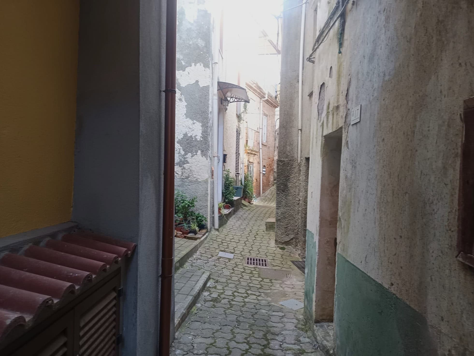Vicolo stretto e pittoresco in un quartiere storico, con pavimentazione in pietra e edifici con pareti in pietra e intonaco, atmosfera autentica e tranquilla.