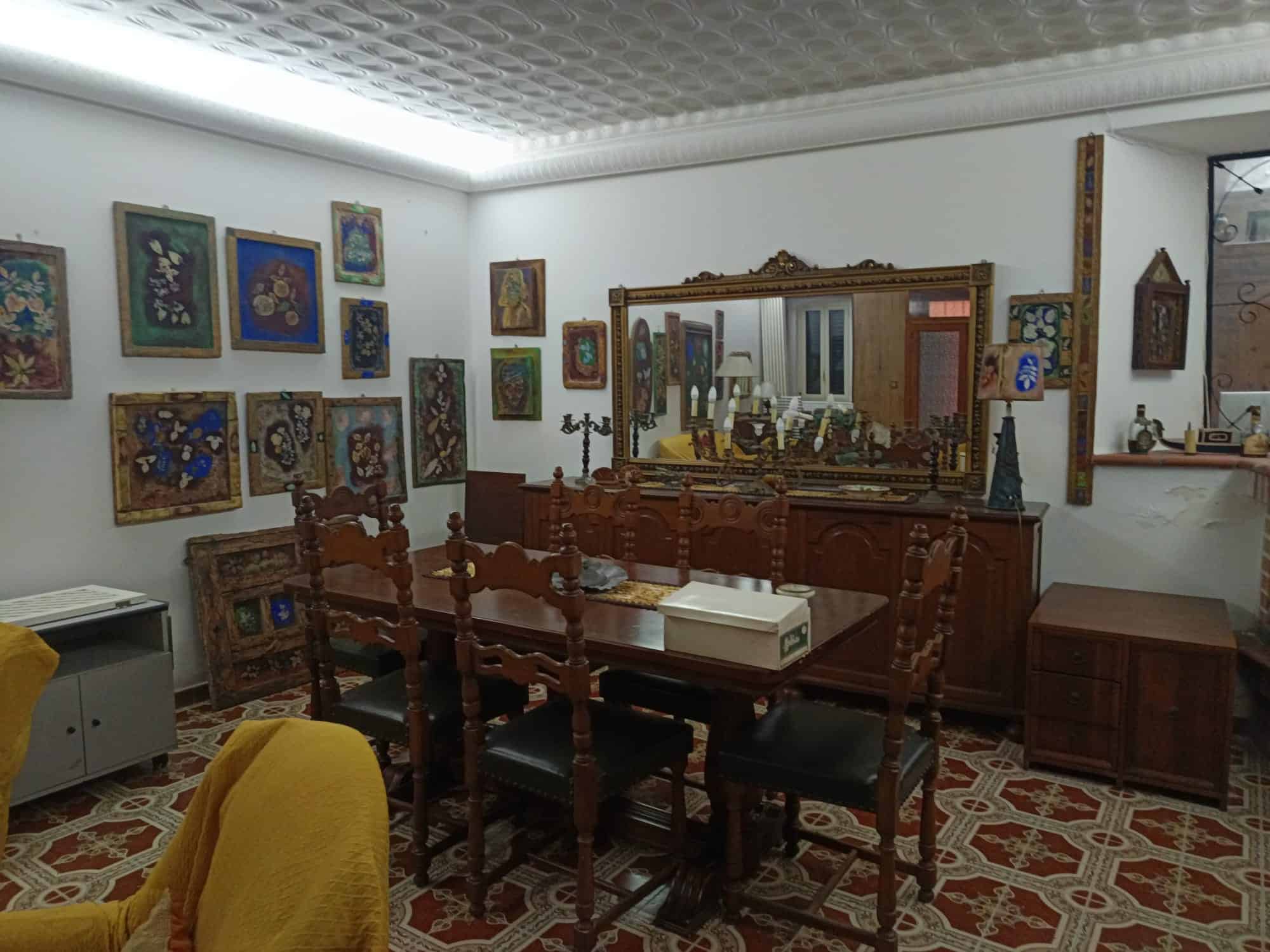 Pannello di decorazioni artistiche e mobili d'epoca in una sala da pranzo elegante con grande specchio e quadri alle pareti, ambiente raffinato e accogliente.