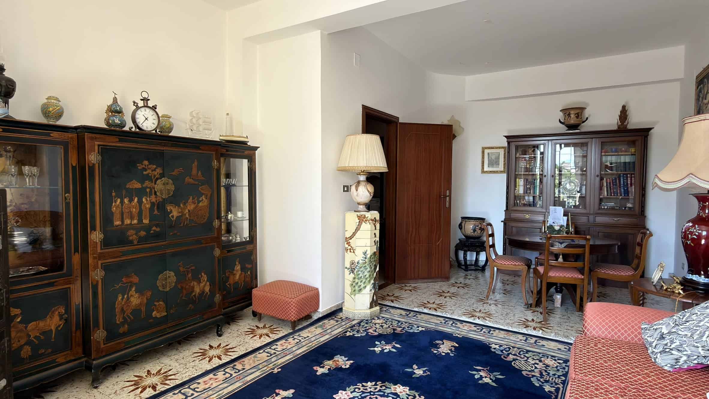 Elegante soggiorno con mobili in stile classico, tappeto persiano e decorazioni vintage, ideale per ambienti raffinati e accoglienti. Perfetto esempio di arredamento tradizionale italiano.