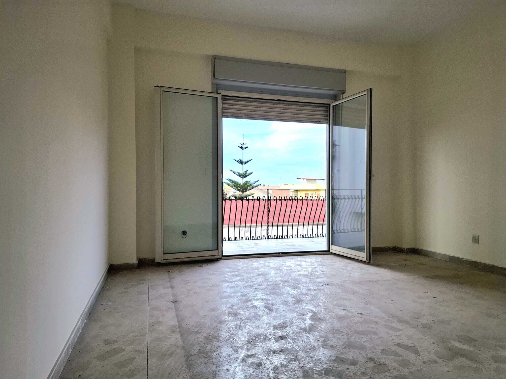 Vetrata scorrevole con balcone e vista panoramica su cielo e alberi, all’interno di una stanza vuota e luminosa, pronta per essere arredata e personalizzata.