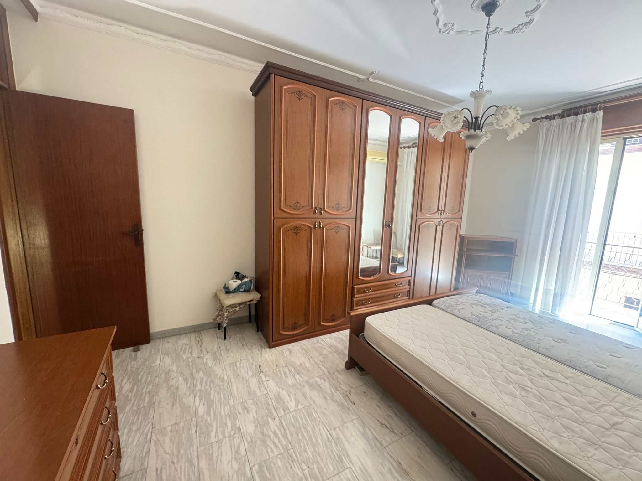 Armadio in legno massiccio e camera da letto con grande finestra e balcone, arredamento classico e luminoso, ideale per appartamenti in centro.