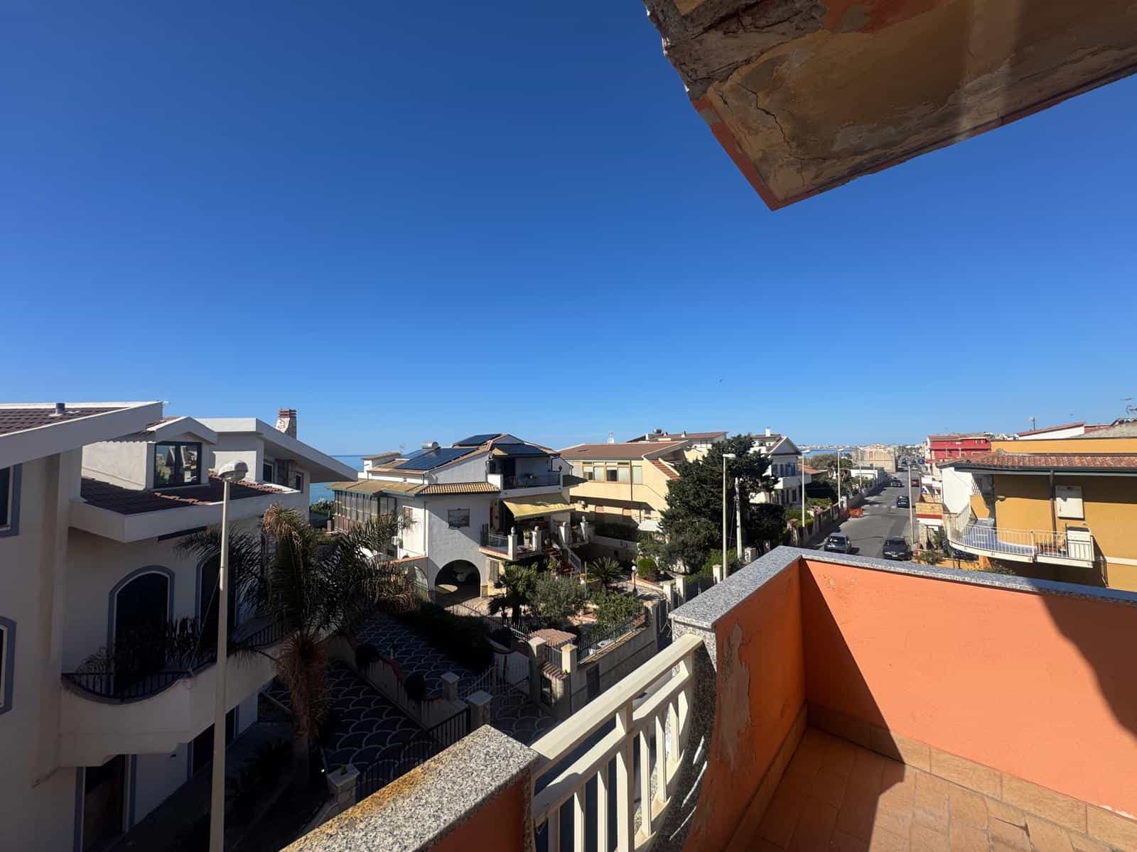 Balcone soleggiato con vista sul quartiere residenziale, case moderne e strade tranquille, cielo azzurro e atmosfera serena, ideale per relax e momenti all'aperto.