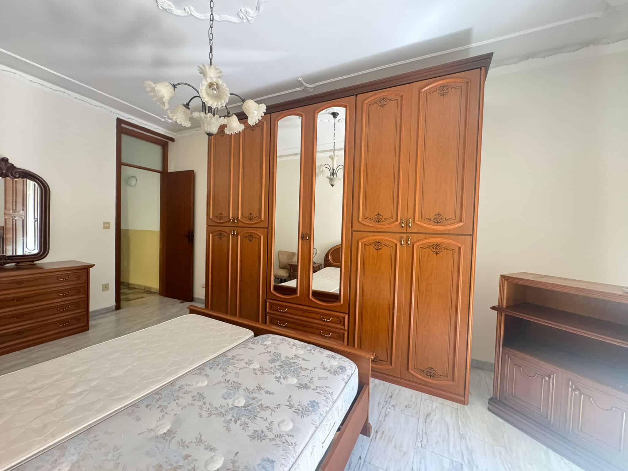 Armadio a muro in legno con specchi, camera da letto spaziosa e luminosa, arredamento classico, dettagli eleganti, ambiente accogliente e ben organizzato, ideale per soggiorno confortevole.