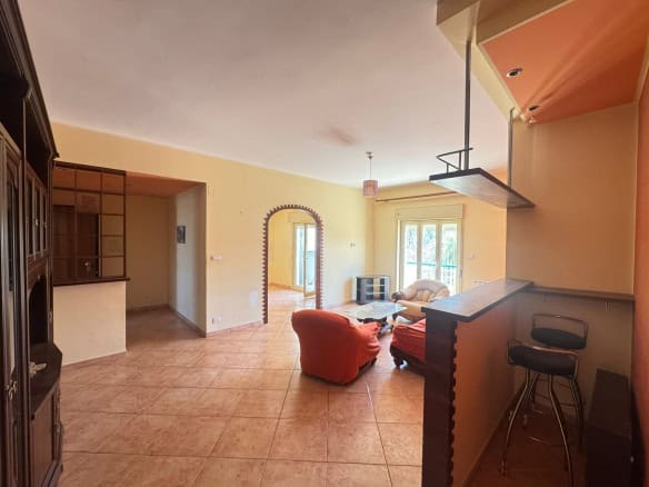 Appartamento spazioso con soggiorno luminoso, arredato con divani e tavolini, con accesso a un balcone e cucina a vista, ideale per vivere in comfort e stile.