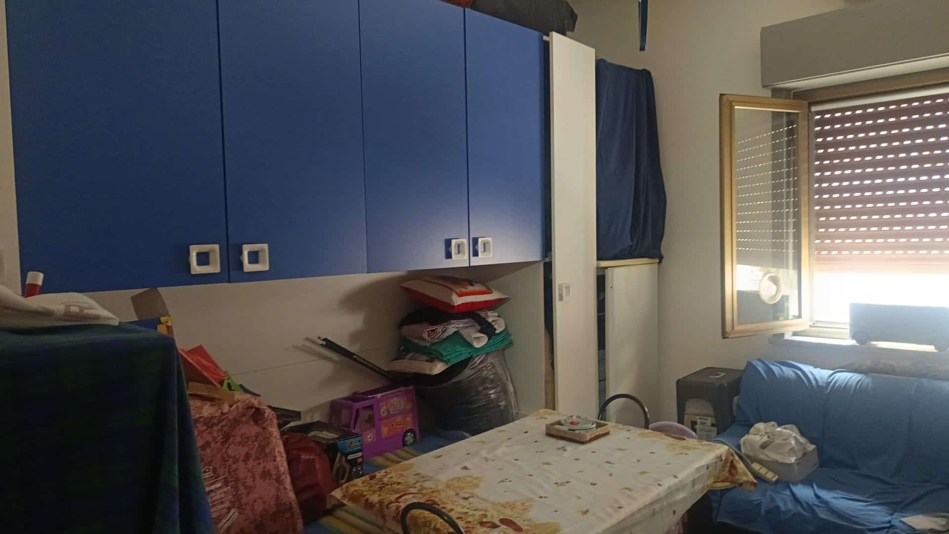 Appartamento con armadio a muro e finestra aperta, arredato con mobili e oggetti vari, in un ambiente domestico luminoso e accogliente.