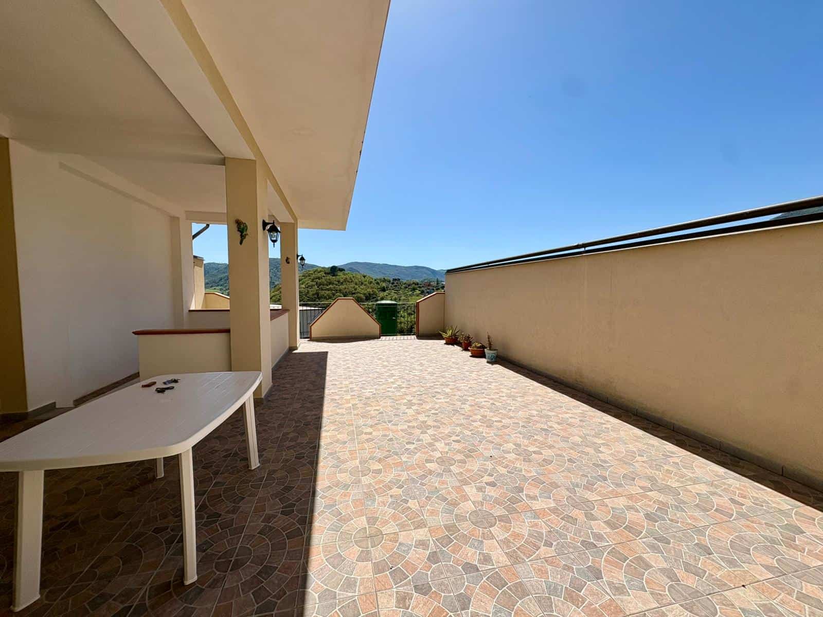 Balcone spazioso con vista panoramica su colline verdi e cielo sereno, pavimentato con piastrelle decorative, ideale per relax e momenti all'aperto in un ambiente tranquillo e luminoso.