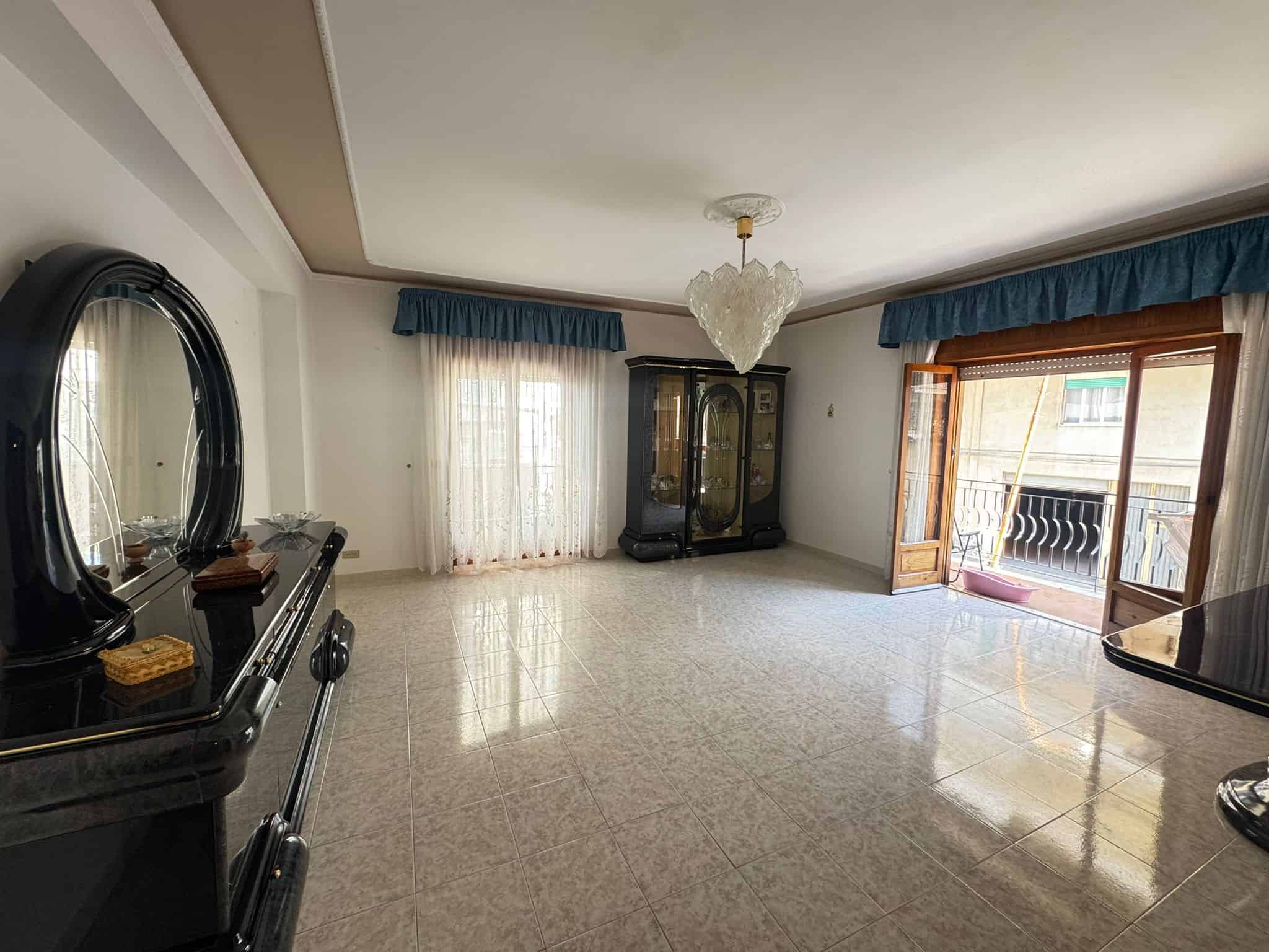 Ampio soggiorno con balcone, luminoso e arredato con mobili classici, ideale per famiglie e relax, con grandi finestre e accesso al balcone.