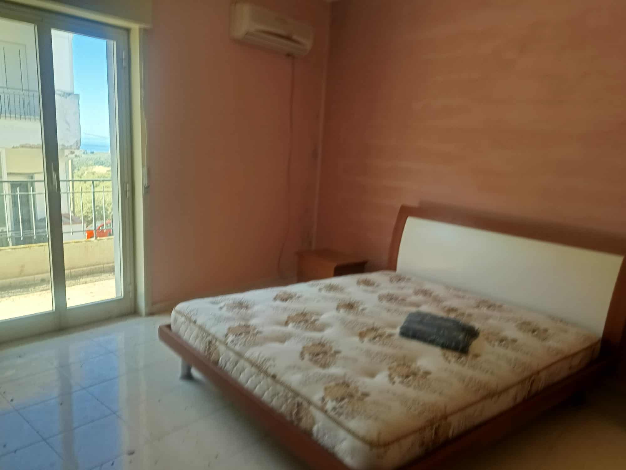 Letto matrimoniale con materasso in una camera luminosa e accogliente, con accesso a un balcone che offre vista panoramica. Ideale per soggiorni confortevoli e rilassanti.