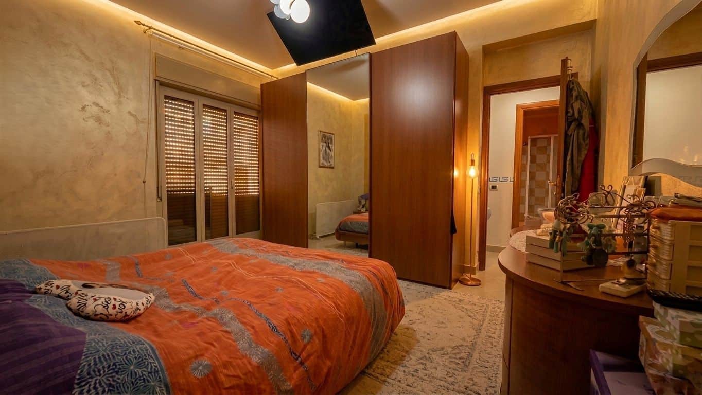 Appartamento con camera da letto arredata, illuminata e accogliente, con mobili in legno e pareti colorate, ideale per soggiorni confortevoli e rilassanti.