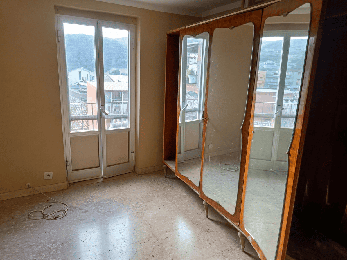 Ampio soggiorno con balcone e grande armadio a specchio, luminoso e spazioso, ideale per rinnovare e personalizzare la tua casa. Vista panoramica sulle montagne e quartiere residenziale circostante.