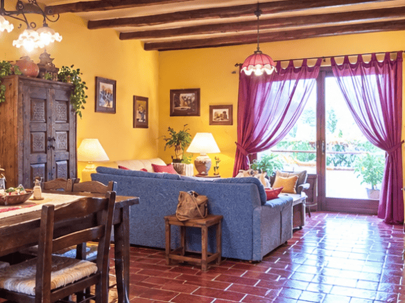 Interno di una villa in vendita a Naso, con soggiorno spazioso, mobili in legno, pareti gialle e decorazioni rustiche, ideale per vivere in Sicilia.