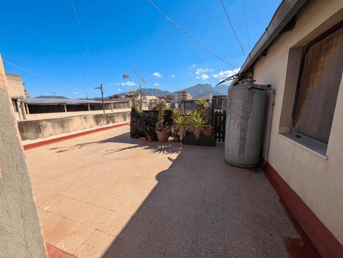 Balcone soleggiato con vista sulle montagne, piante in vaso e spazio aperto, ideale per relax e attività all'aperto.